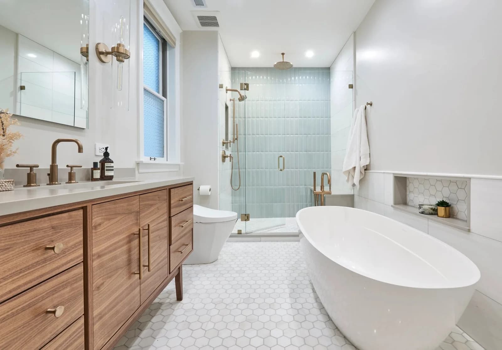 Completed luxury bathroom remodel with white hex tile floors, glass walk-in shower and freestanding tub — the kind of project SEO for bathroom remodelers puts on page one